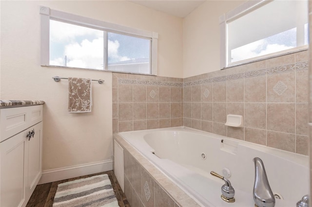 bathroom with tiled tub, vanity, and wood-type flooring