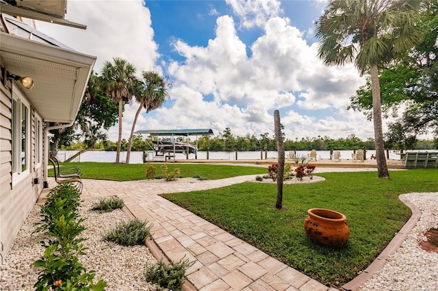 view of community featuring a patio area, a lawn, a dock, and a water view