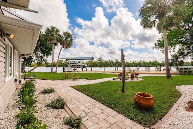 view of yard with a dock, a water view, and boat lift