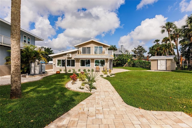 back of house featuring a storage unit, a lawn, and a balcony