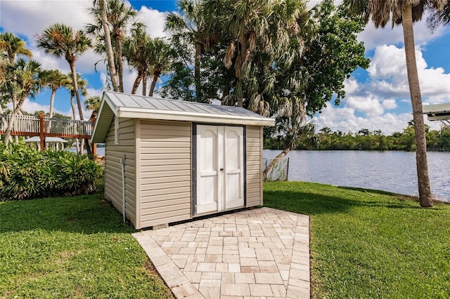 view of outbuilding with a lawn and a water view