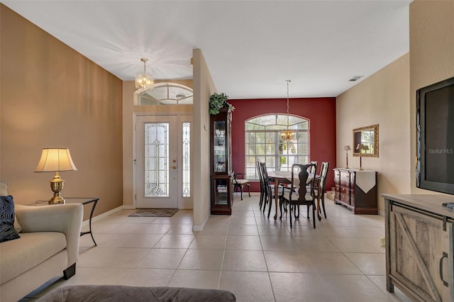 foyer with light tile patterned flooring, visible vents, baseboards, and a notable chandelier