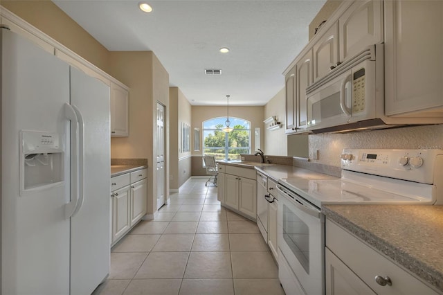 kitchen featuring a sink, light tile patterned flooring, visible vents, pendant lighting, and white appliances