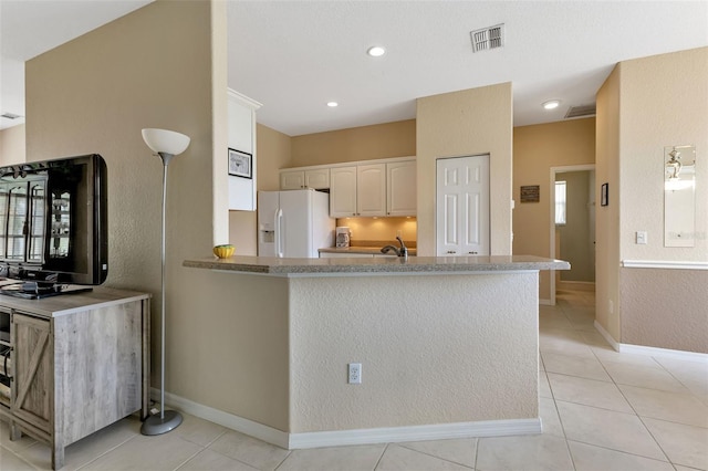 kitchen with kitchen peninsula, sink, white fridge with ice dispenser, and light tile patterned flooring