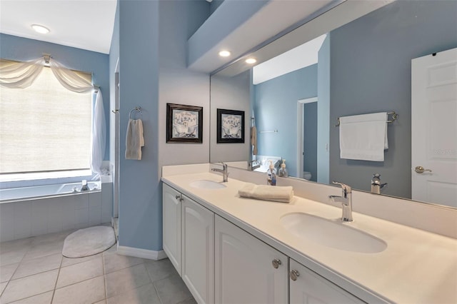 bathroom with tiled tub, vanity, and tile patterned flooring