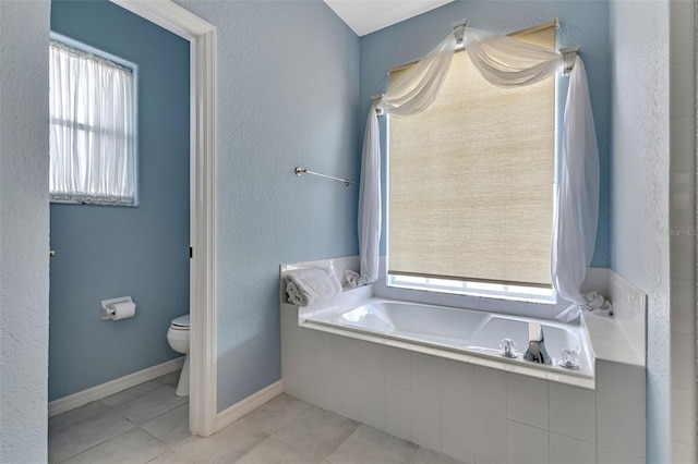 bathroom with plenty of natural light, toilet, a relaxing tiled tub, and tile patterned floors