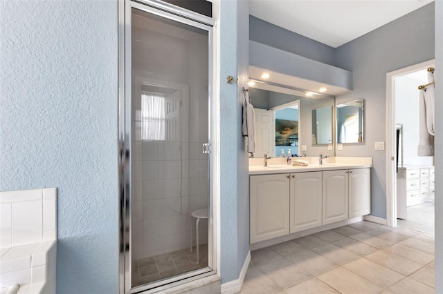 bathroom featuring a textured wall, a sink, double vanity, and a stall shower