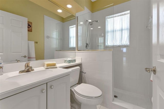 bathroom with tile walls, toilet, plenty of natural light, and vanity