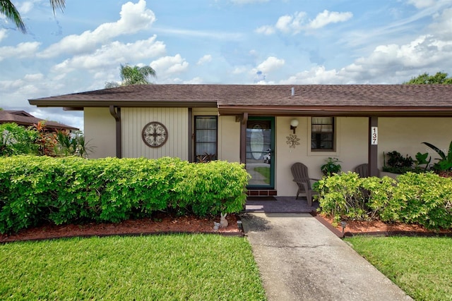 ranch-style home with a shingled roof, a front lawn, and a porch