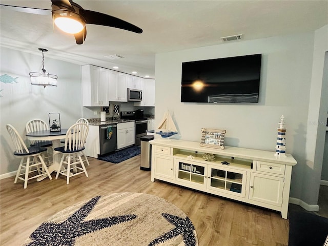 living room with ceiling fan, light hardwood / wood-style floors, and sink