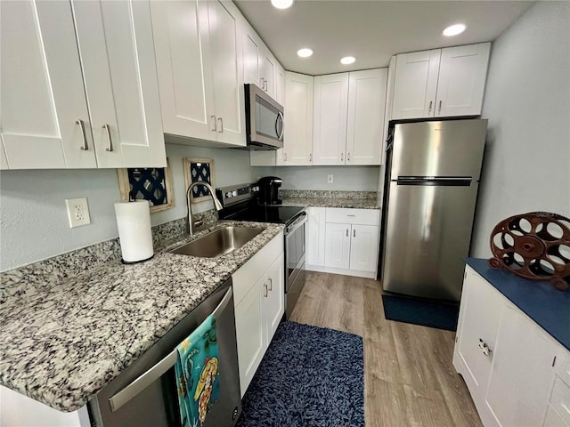 kitchen featuring stainless steel appliances, sink, white cabinetry, and light hardwood / wood-style floors