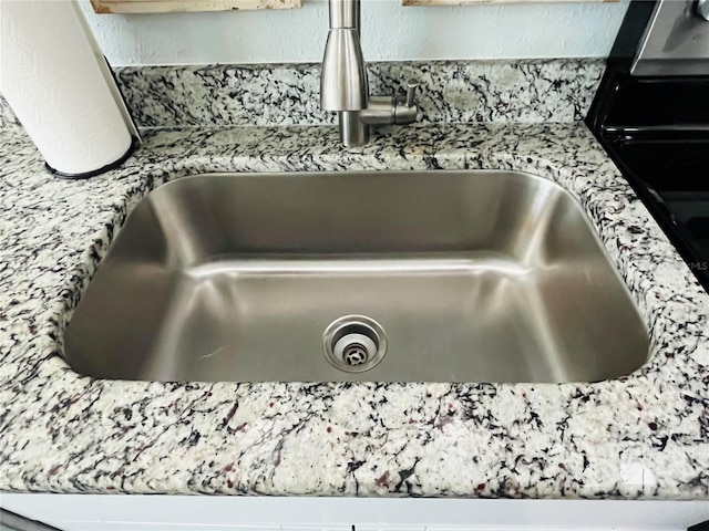 details featuring light stone countertops and sink