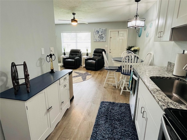 kitchen featuring ceiling fan with notable chandelier, decorative light fixtures, light hardwood / wood-style flooring, stainless steel appliances, and white cabinetry