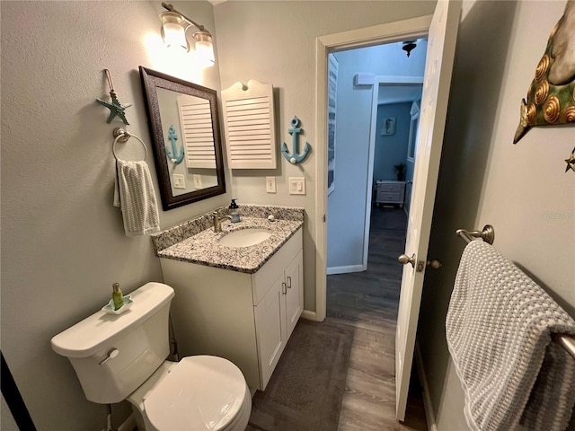 bathroom with vanity, toilet, and hardwood / wood-style flooring