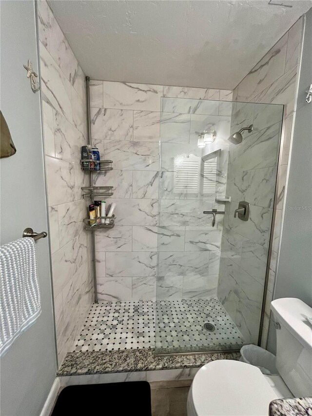 bathroom with toilet, a tile shower, and a textured ceiling