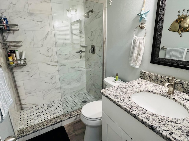 bathroom with tiled shower, vanity, toilet, and hardwood / wood-style floors