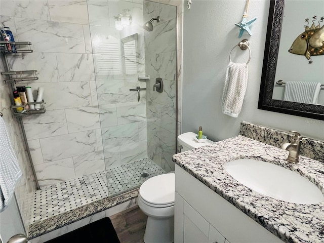 bathroom featuring vanity, a marble finish shower, and toilet