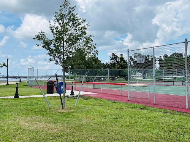 view of sport court with fence and a lawn