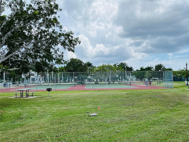 surrounding community featuring tennis court and a lawn