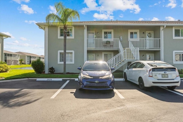 view of property with uncovered parking and stairway