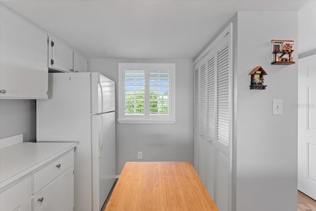 kitchen with white refrigerator, light hardwood / wood-style floors, and white cabinetry