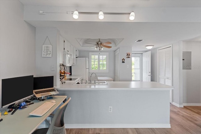 home office with ceiling fan, electric panel, sink, and light hardwood / wood-style flooring