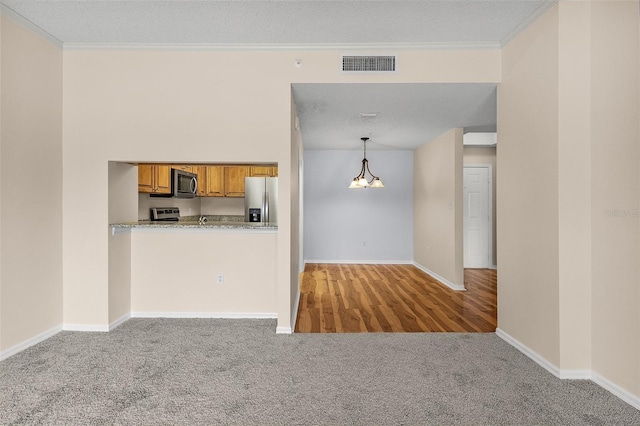 kitchen featuring light colored carpet, stainless steel appliances, visible vents, hanging light fixtures, and brown cabinets