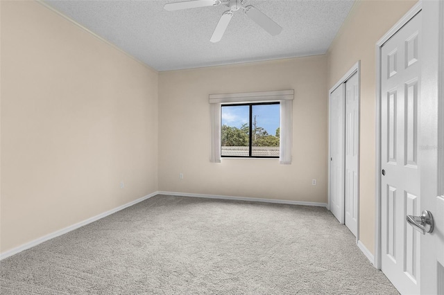 unfurnished bedroom with a textured ceiling, carpet flooring, a ceiling fan, and baseboards