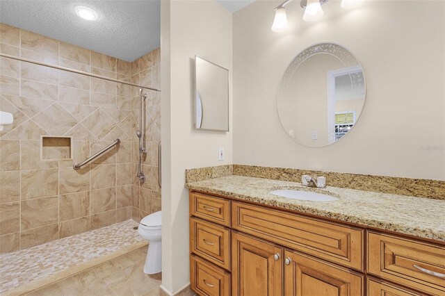 full bath with toilet, a stall shower, a textured ceiling, and vanity