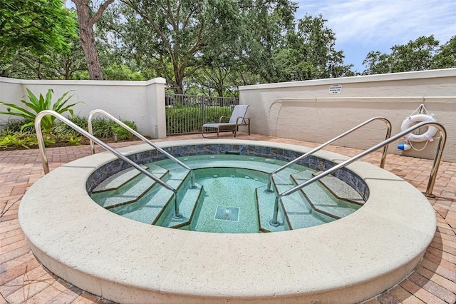 view of pool with a hot tub and fence