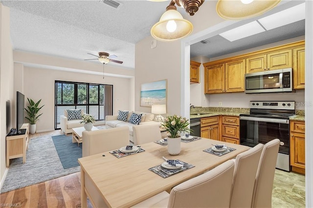 kitchen with visible vents, light stone counters, open floor plan, stainless steel appliances, and a textured ceiling