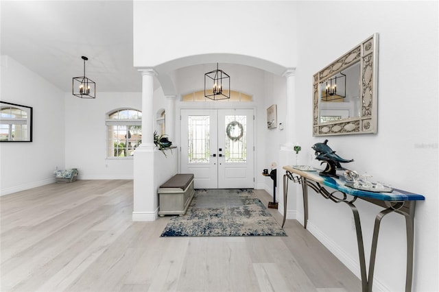 entrance foyer featuring french doors, light hardwood / wood-style flooring, vaulted ceiling, and decorative columns