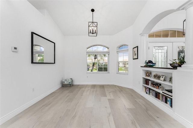 empty room featuring french doors, a chandelier, and light wood-type flooring