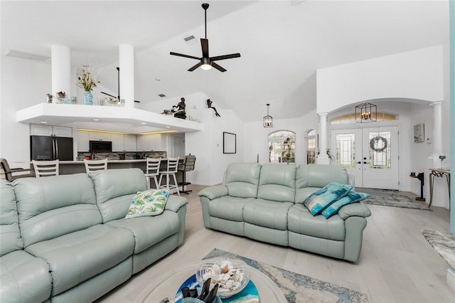 living room featuring ceiling fan, light wood-type flooring, high vaulted ceiling, and french doors