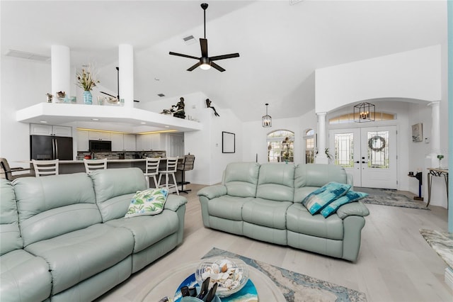 living area with high vaulted ceiling, arched walkways, french doors, and ornate columns