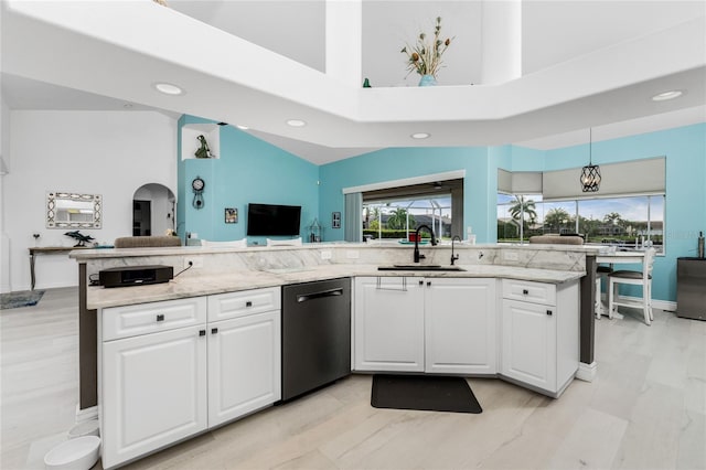 kitchen featuring sink, stainless steel dishwasher, a towering ceiling, decorative light fixtures, and white cabinets