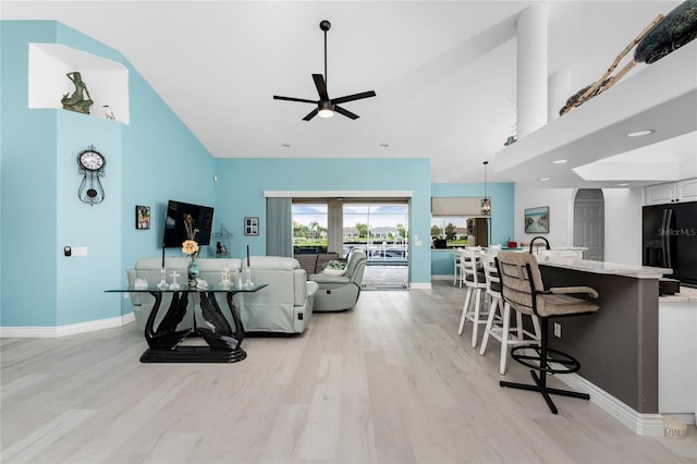 living room featuring ceiling fan, light hardwood / wood-style flooring, a high ceiling, and sink