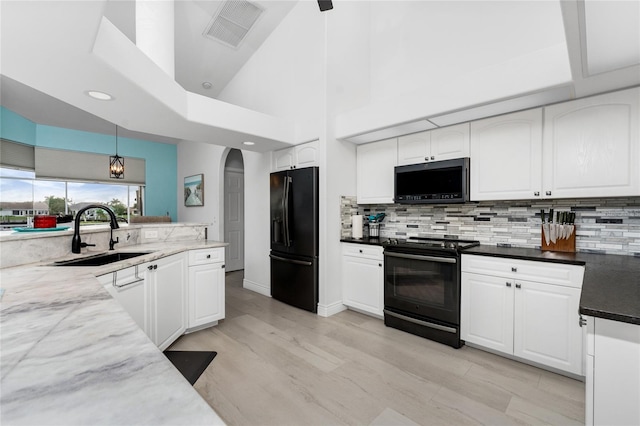 kitchen featuring black appliances, pendant lighting, white cabinets, and a high ceiling