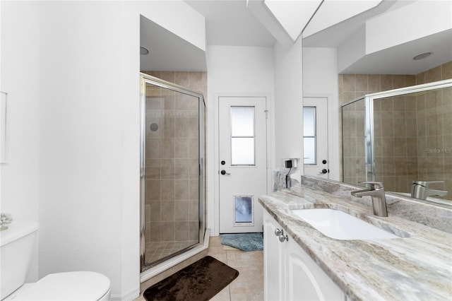 bathroom with tile patterned floors, vanity, toilet, and a shower with shower door