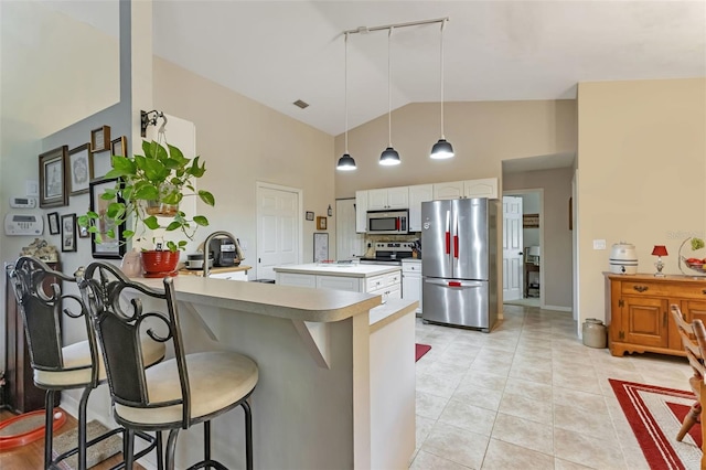 kitchen featuring white cabinets, appliances with stainless steel finishes, kitchen peninsula, a kitchen breakfast bar, and pendant lighting