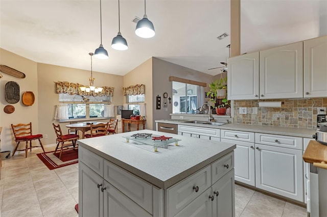 kitchen featuring a kitchen island, ceiling fan with notable chandelier, decorative light fixtures, and tasteful backsplash