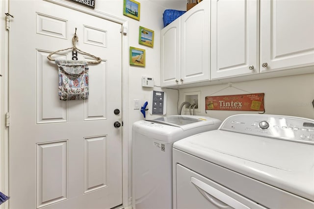 clothes washing area with cabinets and separate washer and dryer