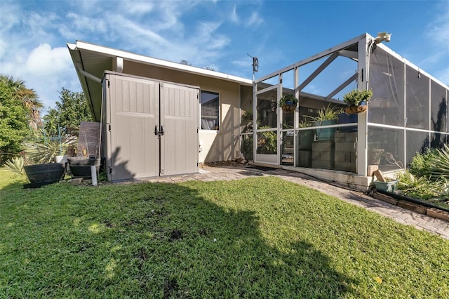 back of house with a lanai, a yard, and a storage shed