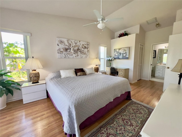 bedroom with a closet, light hardwood / wood-style floors, ensuite bath, lofted ceiling, and ceiling fan