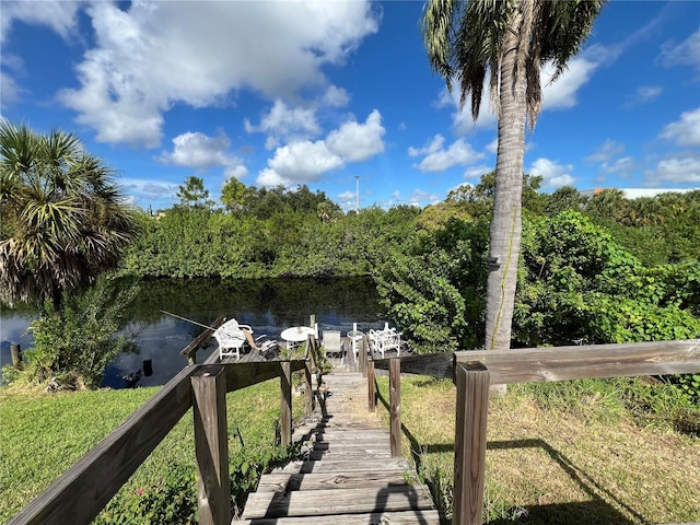 view of dock with a water view and a lawn