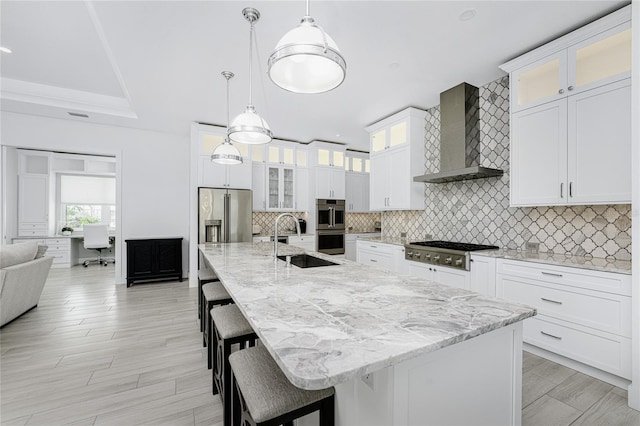 kitchen with wall chimney exhaust hood, a center island with sink, and pendant lighting