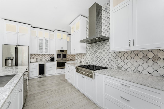 kitchen with light stone counters, stainless steel appliances, white cabinetry, wall chimney exhaust hood, and wine cooler