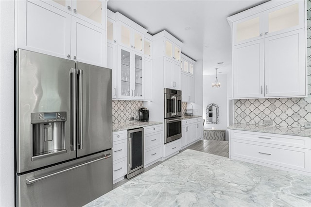 kitchen featuring white cabinets, hanging light fixtures, stainless steel appliances, and wine cooler