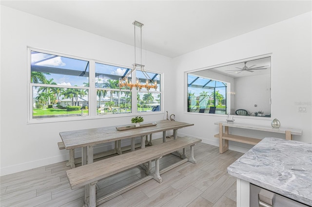 dining space with ceiling fan with notable chandelier and light hardwood / wood-style floors