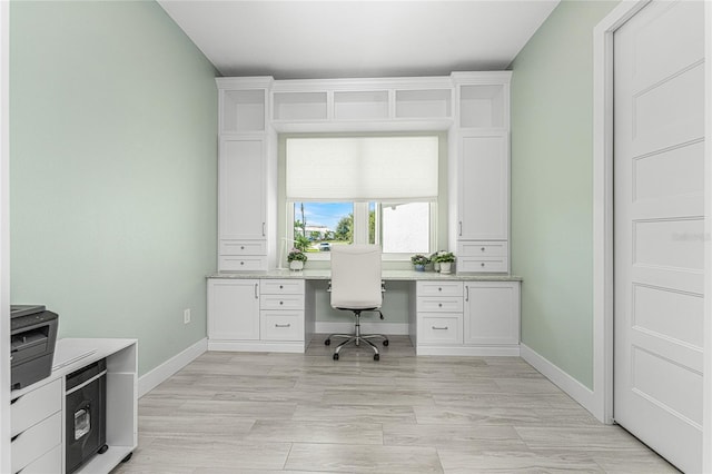 office space with built in desk and light hardwood / wood-style floors